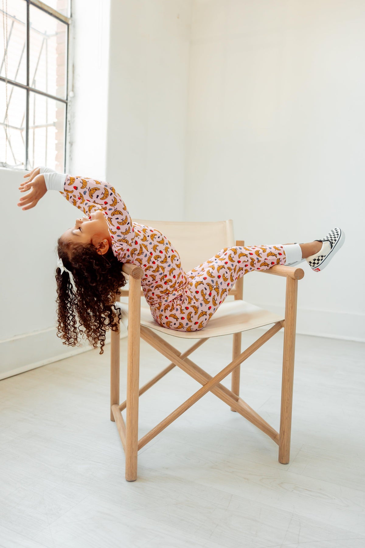 girl in croissant pajamas sitting in chair