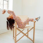 girl in croissant pajamas sitting in chair